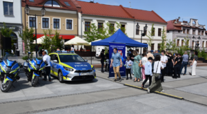 Policyjne motocykle oraz radiowóz oraz osoby przechodzące płytą rynku
