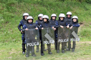 Policjanci przy tarczach z napisem policja
