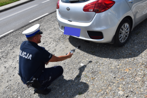 policjant z sonometrem przy samochodzie