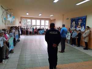 Uczniowie trzymający plakaty oraz policjant