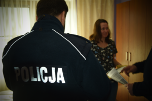 Policjanci oraz kobieta trzymają ulotki informacyjne
